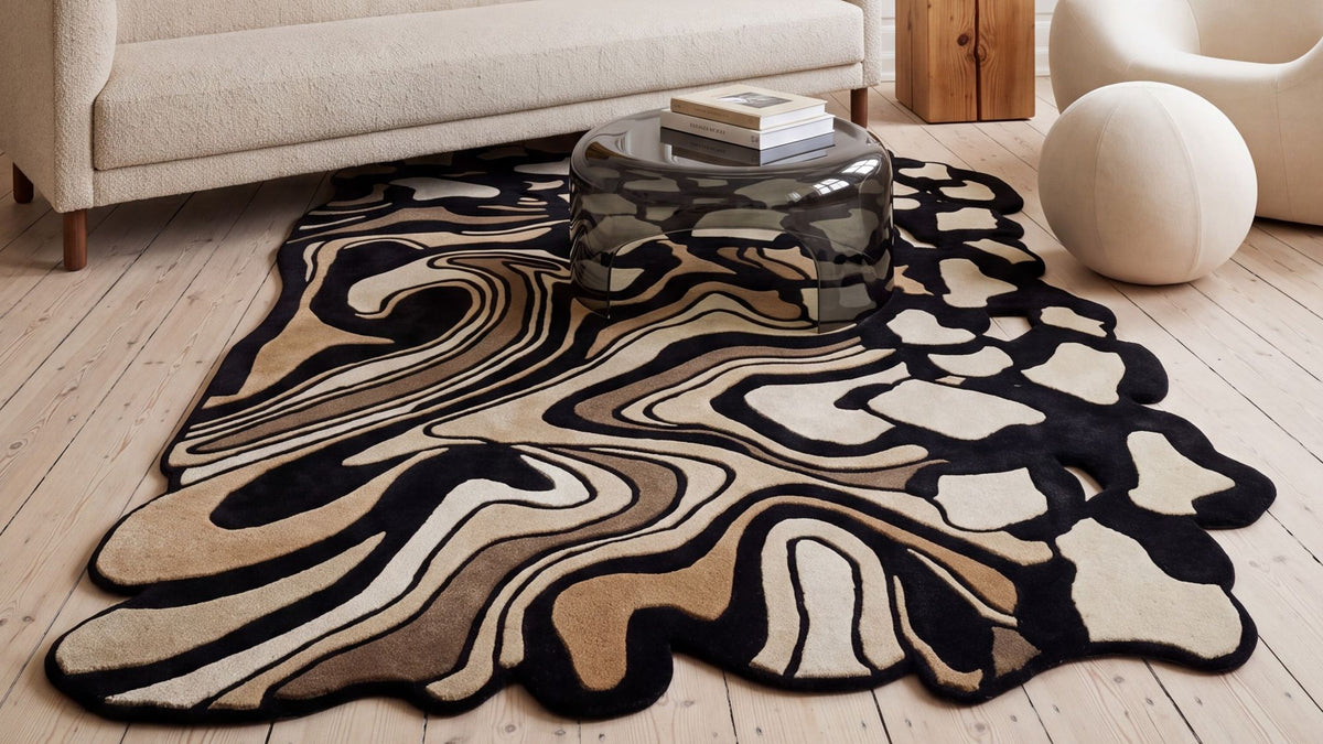 Amal Rug in a living room, a shaped hand tufted wool and Botanical Silk rug in front of a pale sofa.