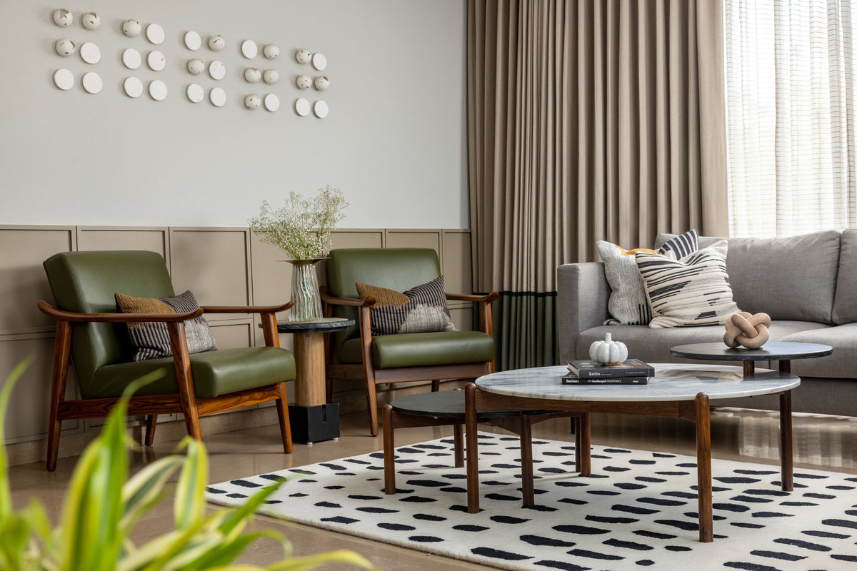 Arctic Wool Rug in a real Indian living room, beneath green armchairs with wooden frames and a round marble table.