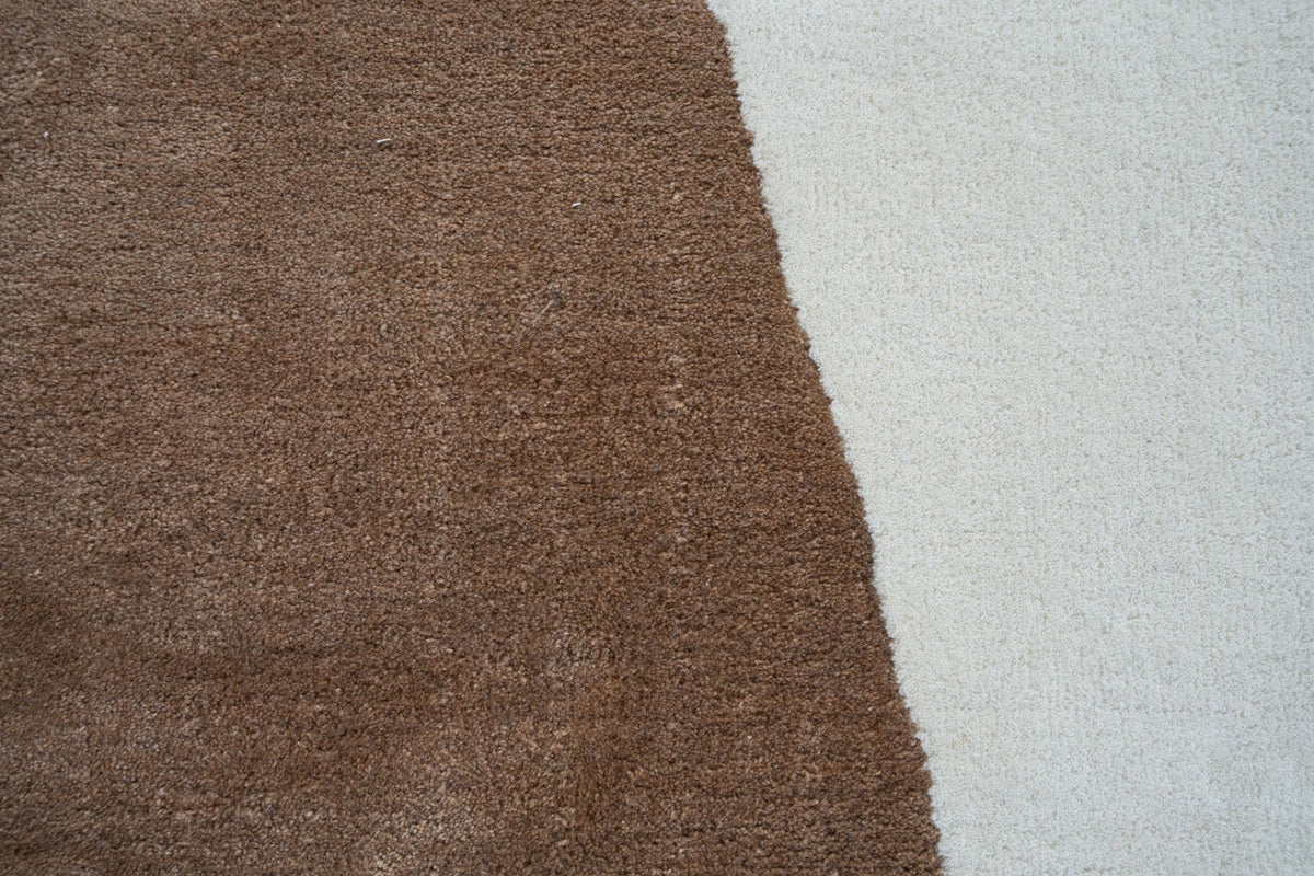 Bias Wool Rug close up, hand tufted New Zealand wool in warm brown meeting an ivory field.