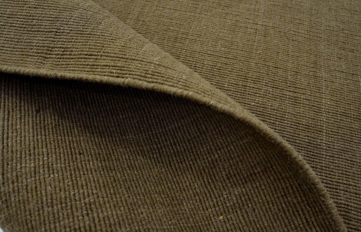 Cabra Wool & Jute Rug in Olive folded over, a low handloom weave of New Zealand wool and jute with a firm, flat surface.