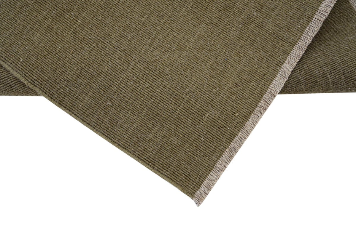 Cabra Wool & Jute Rug in Olive folded at the corner, a flat handloom weave of New Zealand wool and jute.