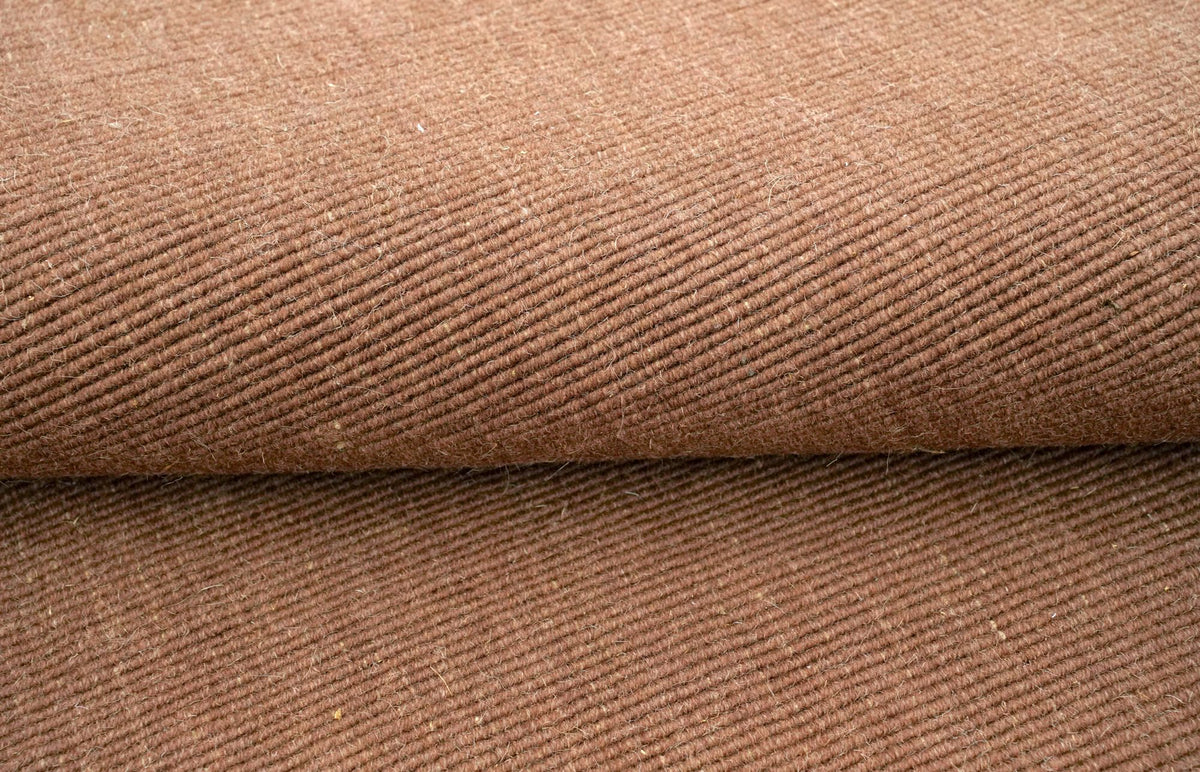 Cabra Wool & Jute Rug in Rust folded, a dry, flecked clay colour in handloom New Zealand wool and jute.