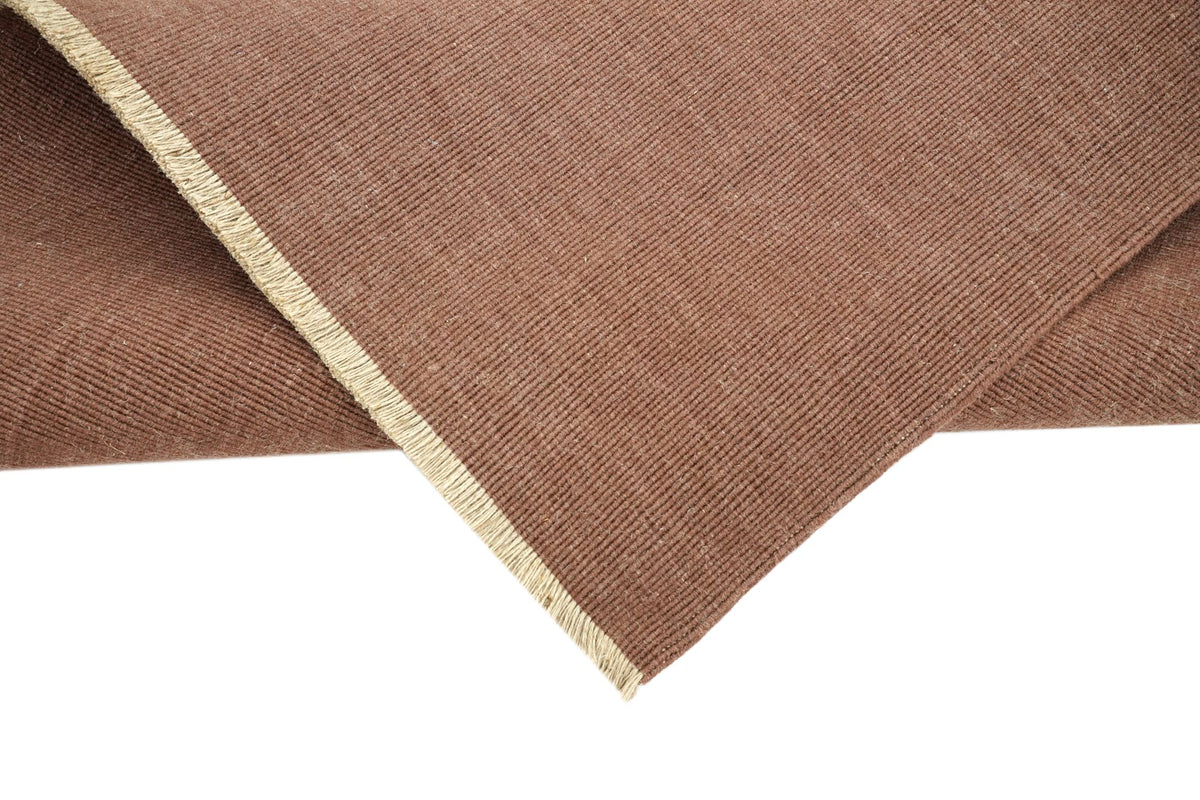 Cabra Wool & Jute Rug in Rust turned at the corner, with its pale jute edge.