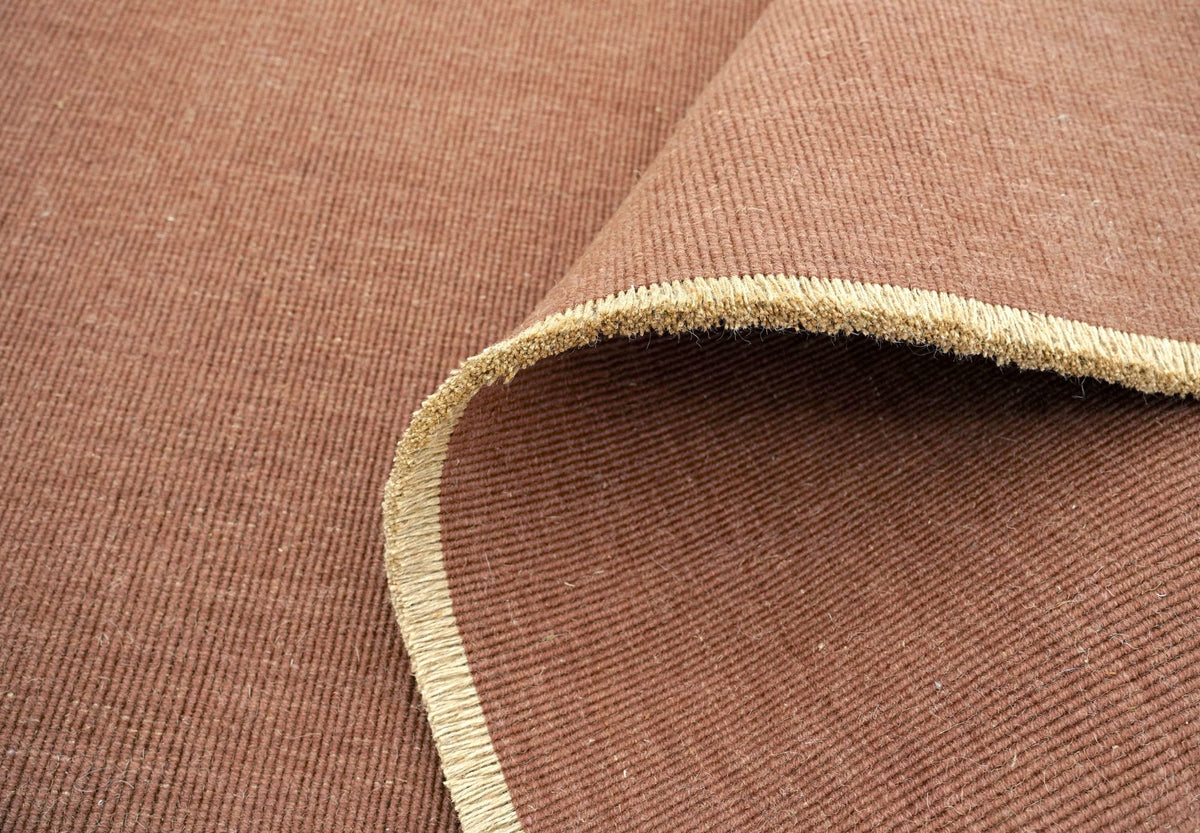 Cabra Wool & Jute Rug in Rust turned back at the corner, a firm handloom weave of New Zealand wool and jute.