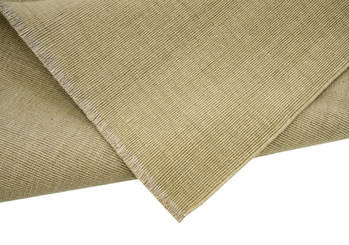 Cabra Wool & Jute Rug in Sand folded at the corner, handloom New Zealand wool and jute with a fringed end.