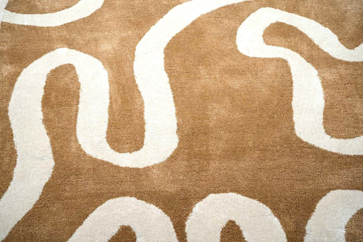 Congrand Wool Rug close up, hand tufted New Zealand wool with ivory looping lines on a warm tan ground.