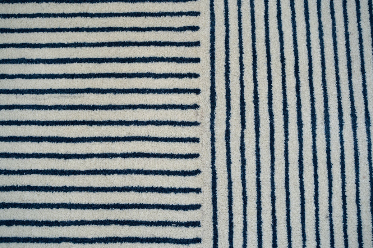 Eucalyptus Wool Rug close up, fine dark stripes on ivory that change direction down the middle.
