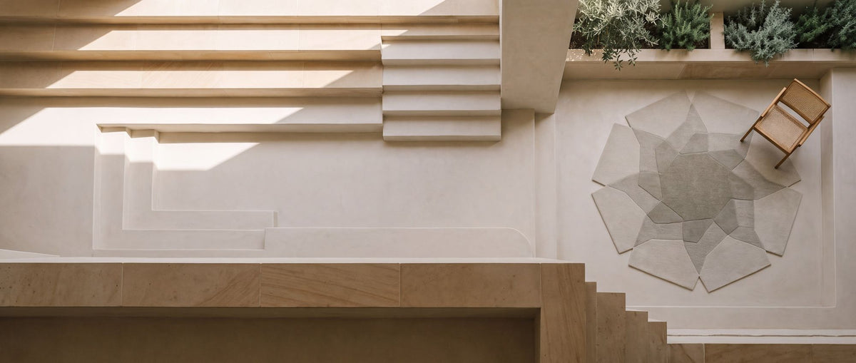 Facet Wool Rug seen from above on a pale stone terrace, hand tufted New Zealand wool with carved planes.