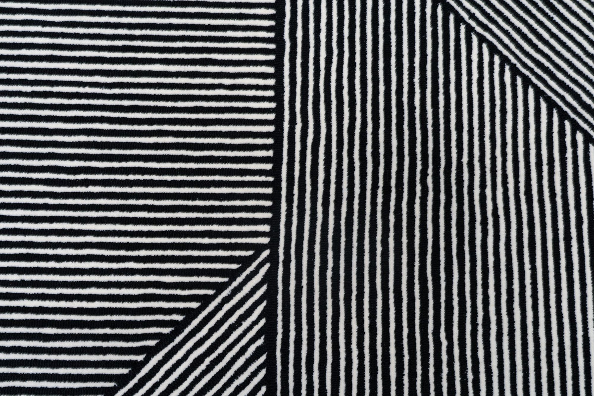 Flair Wool Rug close up, black and ivory stripes in hand tufted New Zealand wool, changing direction block by block.