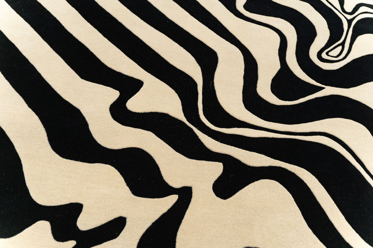Fluid Wool Rug close up, hand tufted New Zealand wool drawn in black and ivory curves.