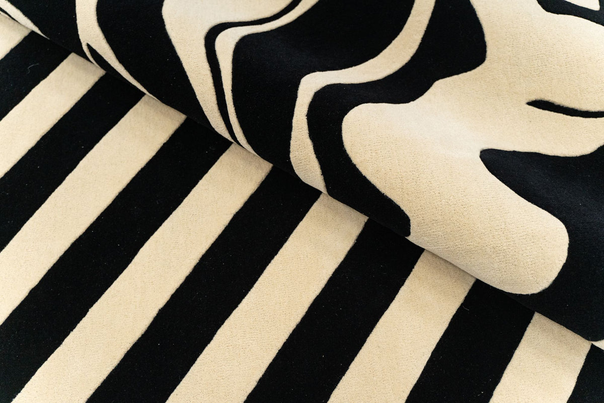 Fluid Wool Rug folded, hand tufted New Zealand wool in black and cream curves with black and cream stripes.