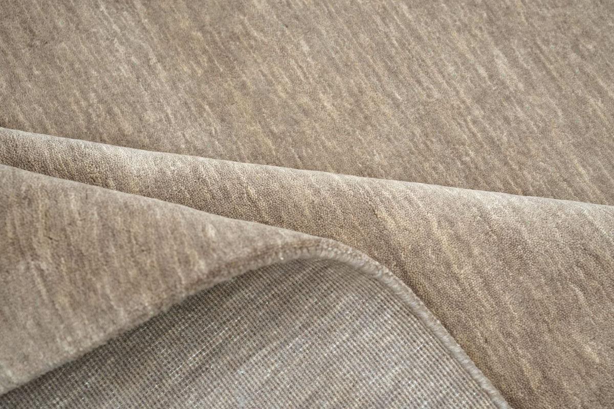 Grain Wool Rug in Mochaccino folded at the corner, a low handloom weave of New Zealand wool.