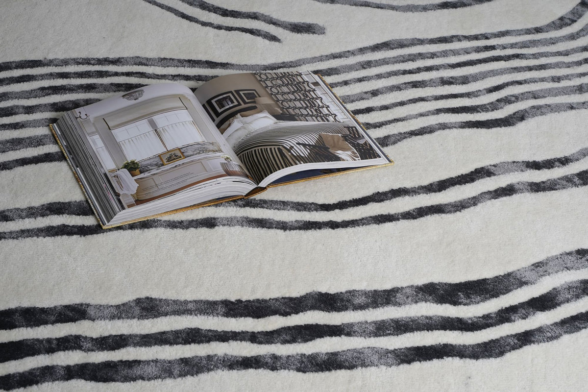 Livid Wool & Silk Rug with an open book, hand tufted New Zealand wool and silk, charcoal strokes on a pale ground.