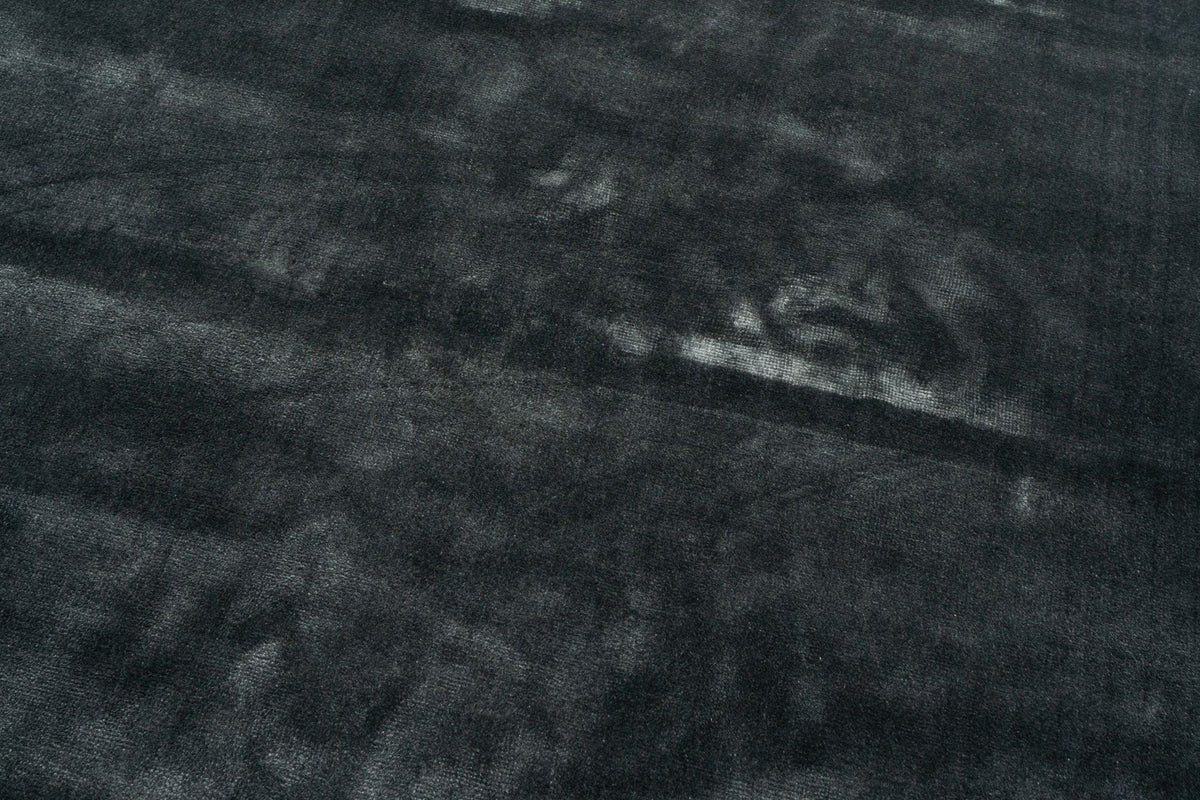 Luma Botanical Silk Rug in Charcoal close up, the handloom surface turning silver where the light rakes across it.