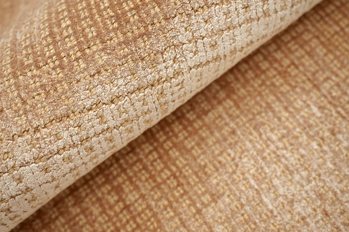 Meraki Jute & Silk Rug in Caramel turned back on itself, threads of silk lifting a handloom jute grid.