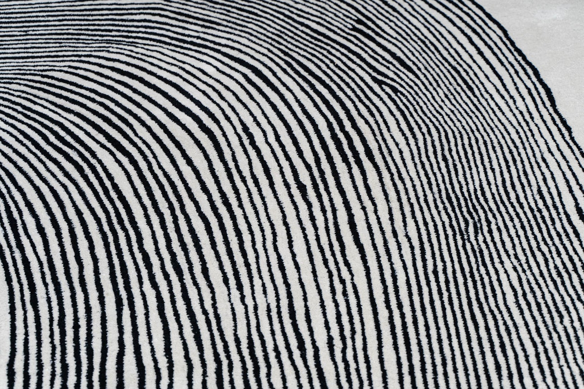 Monochrome Wool Rug close up, hand tufted New Zealand wool in fine black lines fanning across ivory.