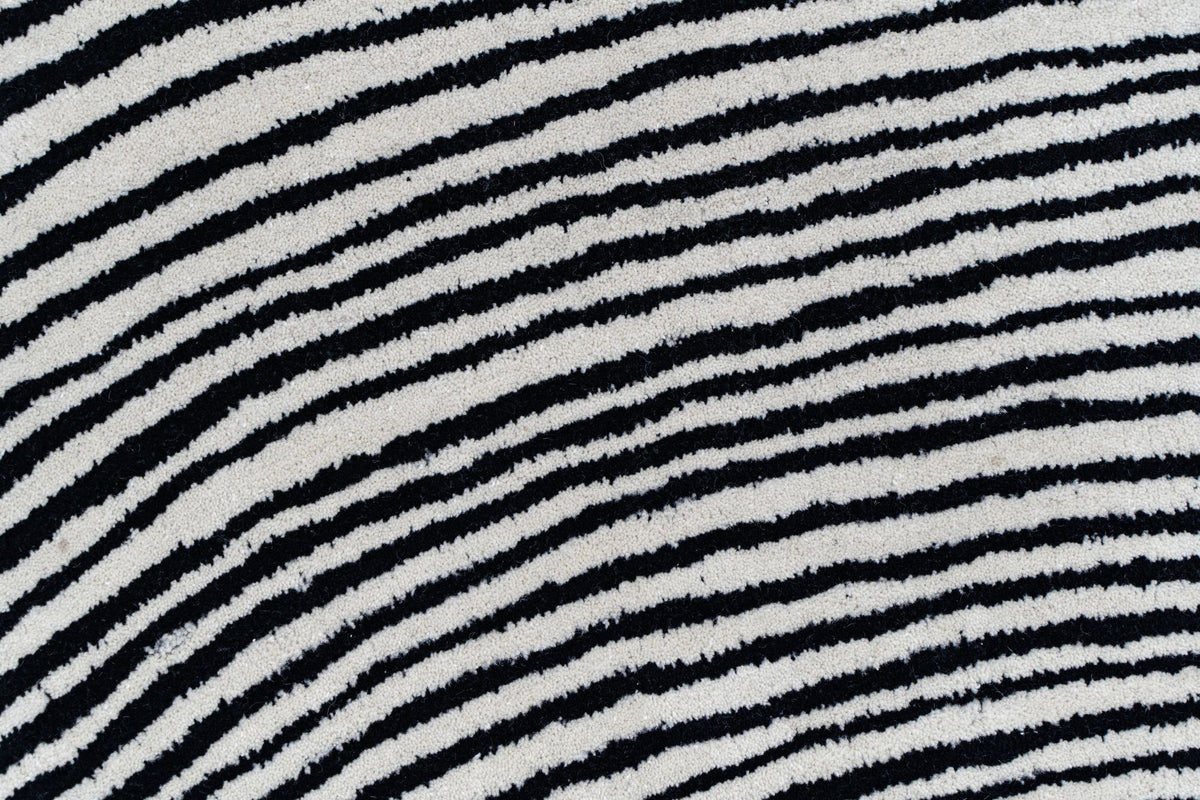 Monochrome Wool Rug close up, hand tufted New Zealand wool with dense black and ivory lines running across the pile.