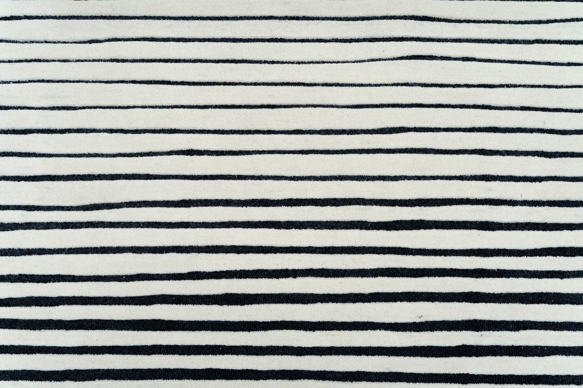 Oblique Wool Rug close up, black lines ruled across ivory hand tufted New Zealand wool.