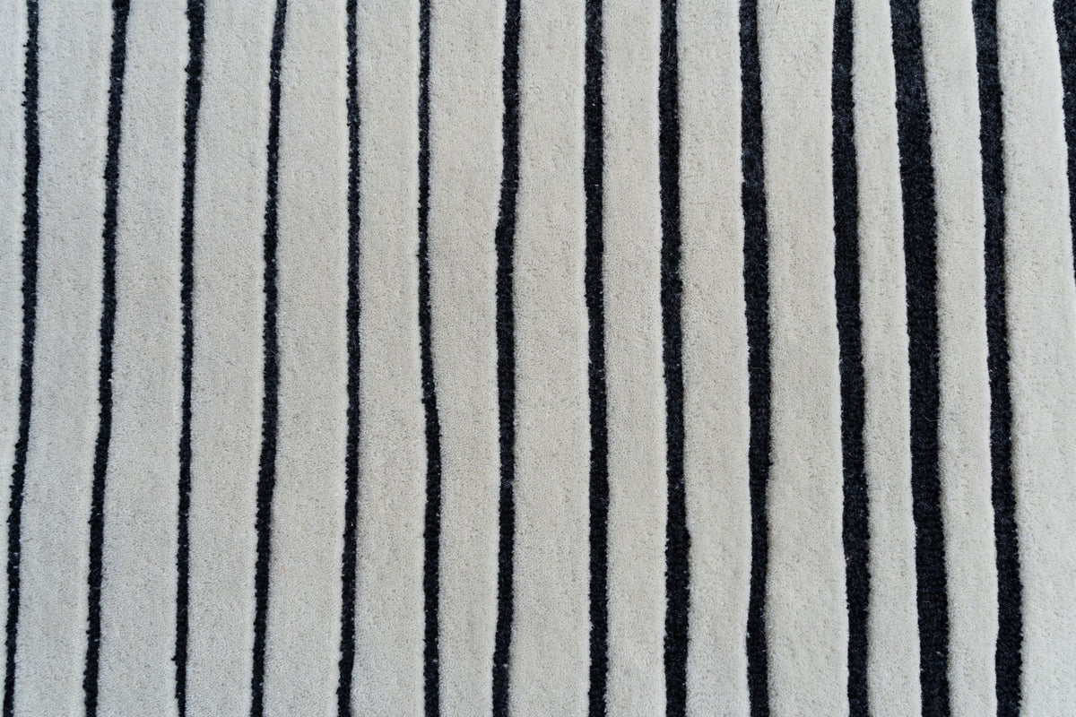 Oblique Wool Rug close up, black lines drawn by hand across ivory hand tufted New Zealand wool, each one slightly irregular.