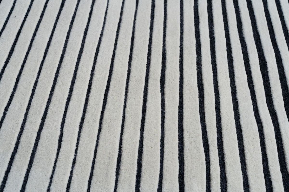 Oblique Wool Rug close up, dark lines running across an ivory hand tufted New Zealand wool pile.