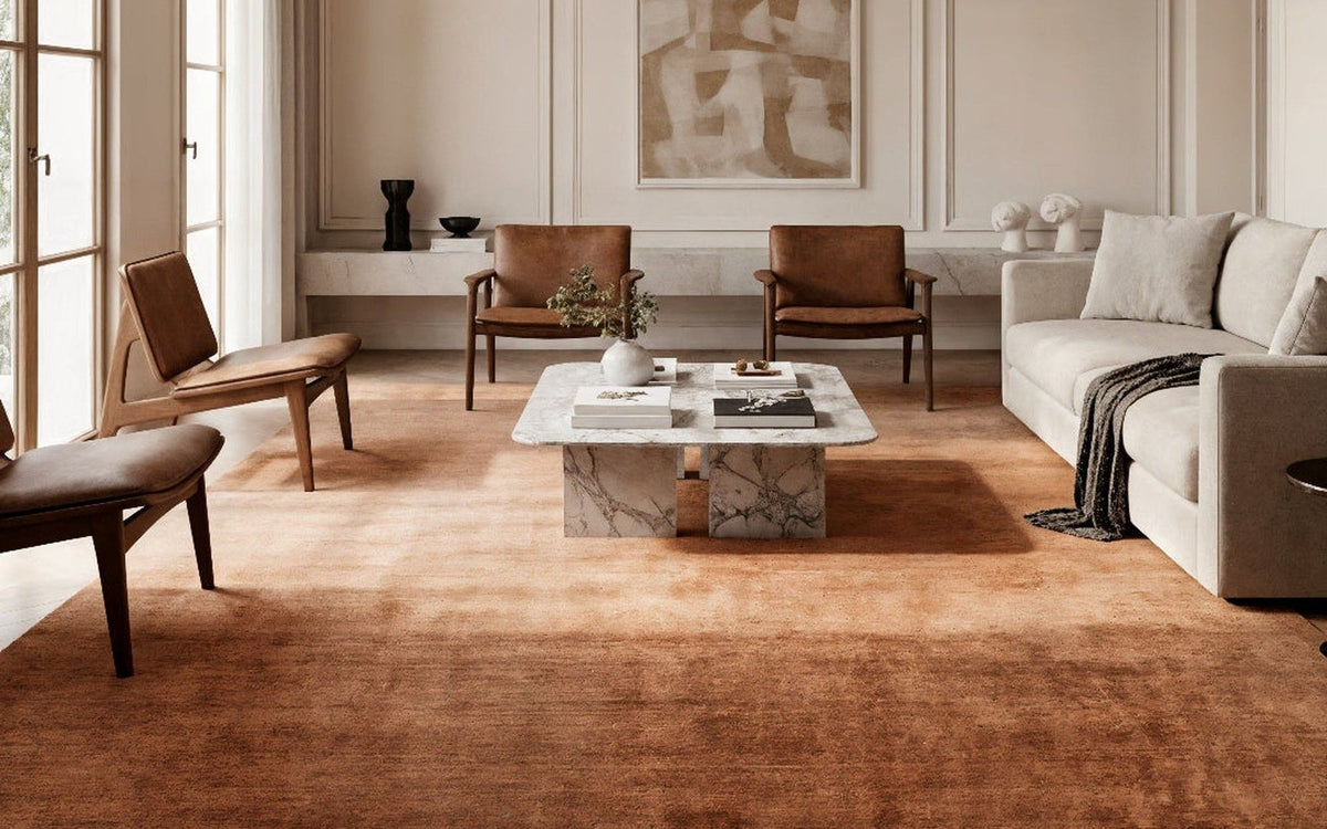 Plush Wool Rug in Copper in a drawing room, a deep handloom wool pile under a sofa, marble table and leather chairs.