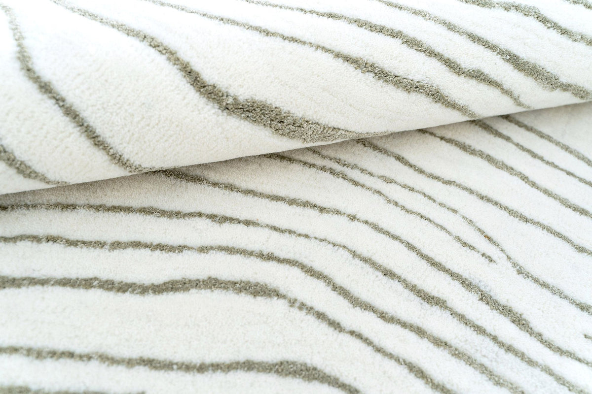 Trickle Wool & Silk Rug close up, pale sage marks running slowly across an ivory field of hand tufted New Zealand wool and Botanical Silk.
