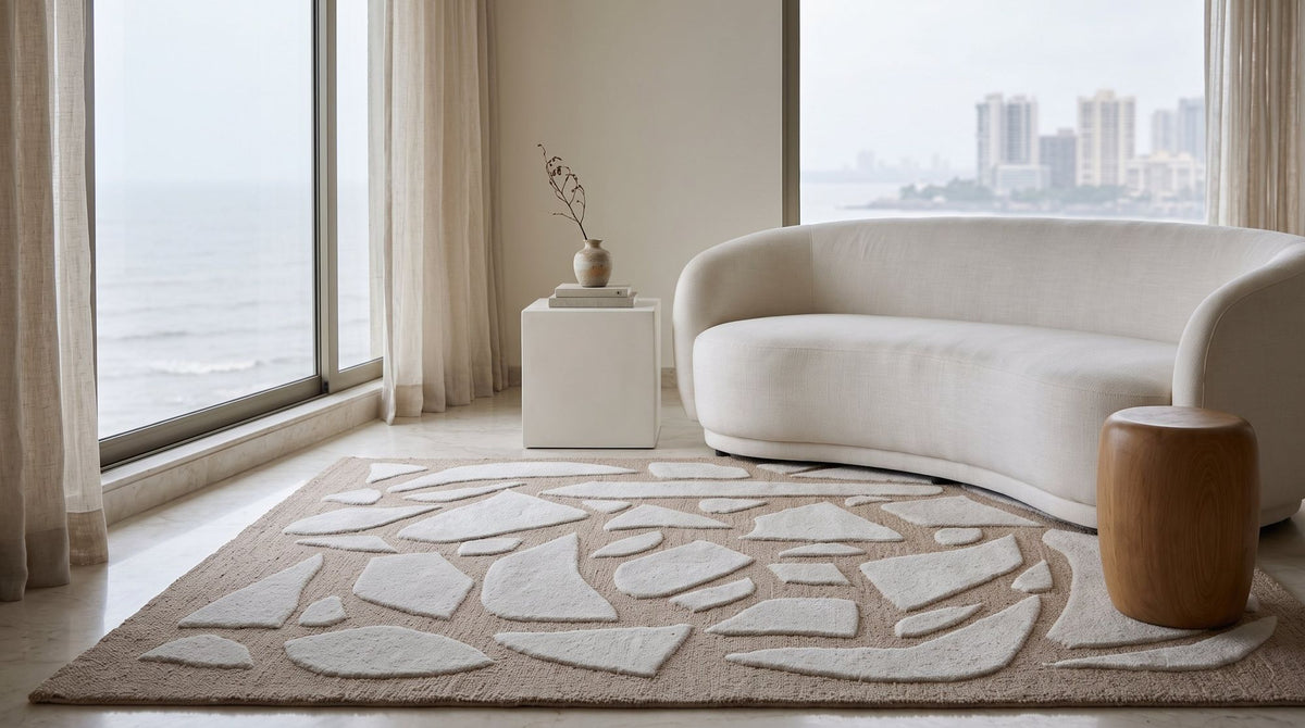 Bergamo Rug in a styled living room facing the sea, hand tufted New Zealand wool in ivory shapes on sand.
