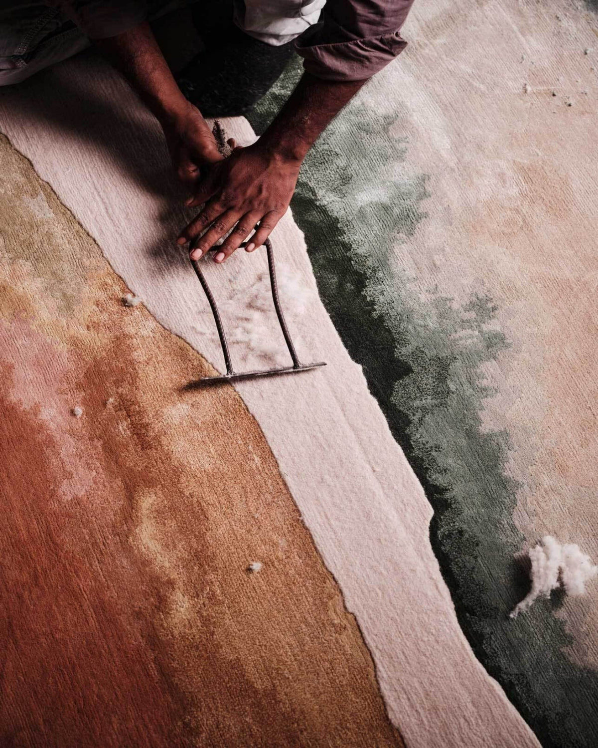 Hand finishing the surface of a newly woven rug
