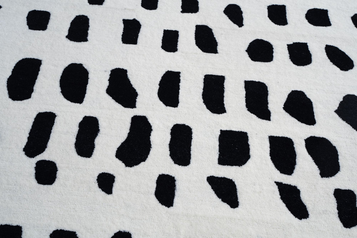 Arctic Wool Rug close up, black brushstroke marks on a pale hand tufted New Zealand wool ground, a pattern that can carry a 12x15 ft floor.