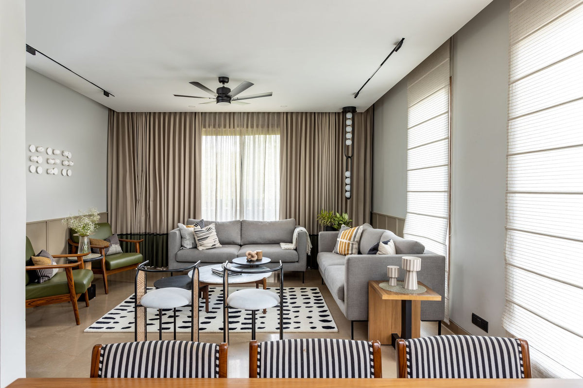 Arctic Wool Rug in a long, pale living room with grey sofas and green lounge chairs, hand tufted New Zealand wool.