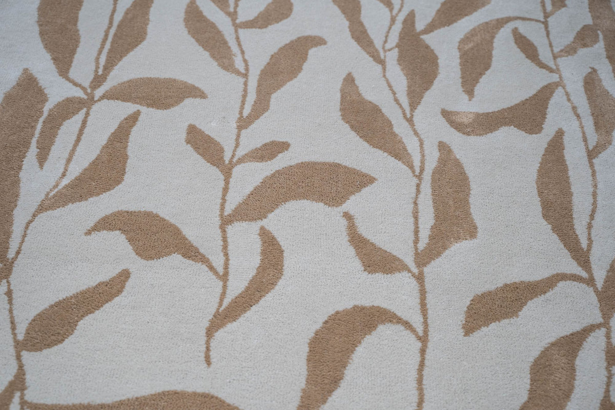 Botanical Wool Rug close up, hand tufted ivory New Zealand wool with a pattern of tan leaves on slender stems.