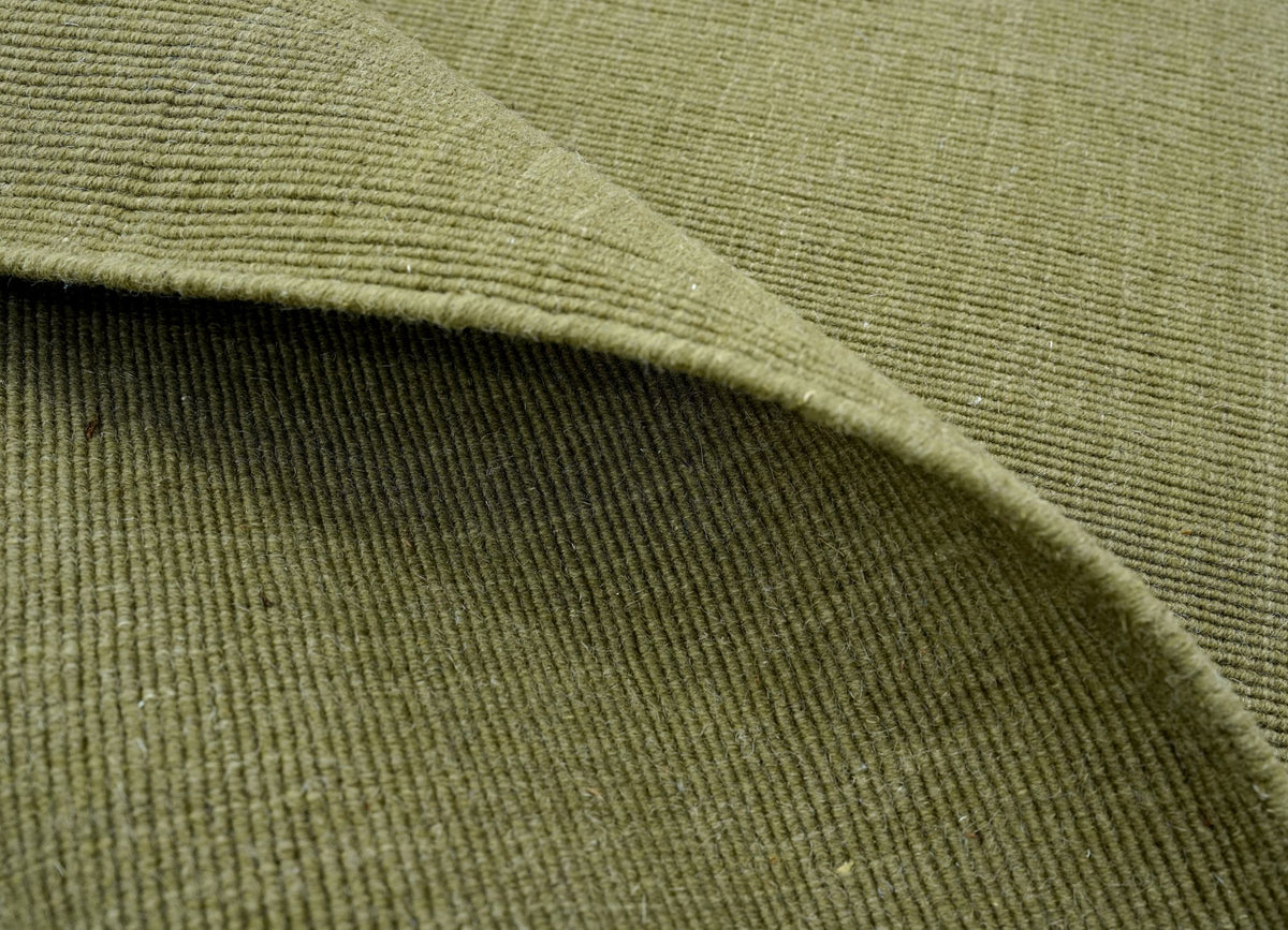 Cabra Wool & Jute Rug in Olive folded at the corner, handloom New Zealand wool and jute in a muted green.