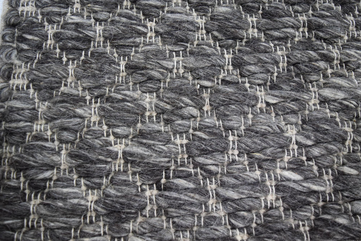 Cobble Wool Rug close up, handwoven New Zealand wool in a charcoal and grey nubbed weave.