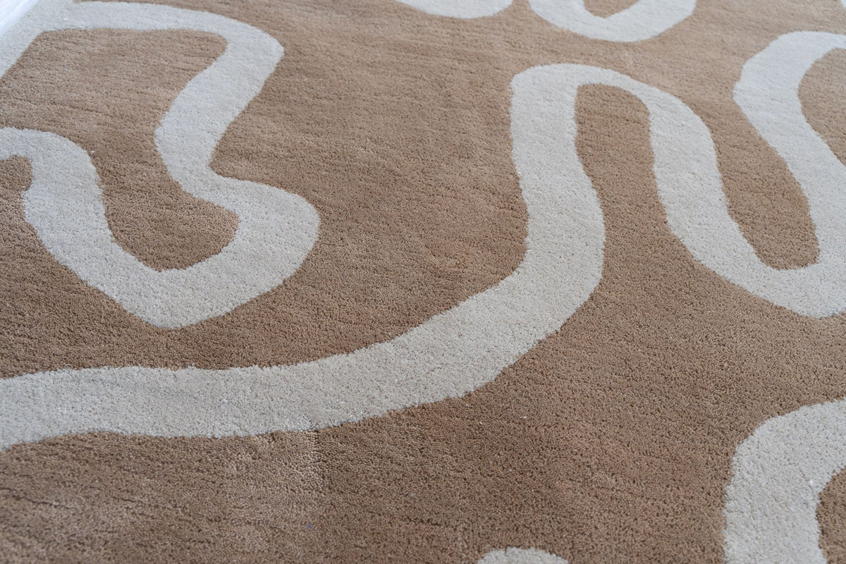 Congrand Wool Rug close up, hand tufted New Zealand wool in camel with broad looping forms in pale grey.