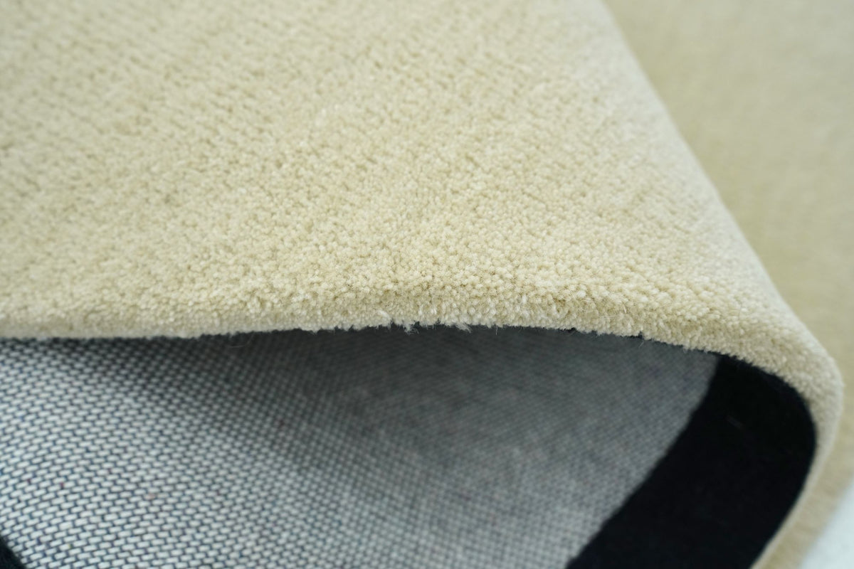 Facet Wool Rug folded at the edge, a pale hand tufted New Zealand wool pile over its backing cloth.