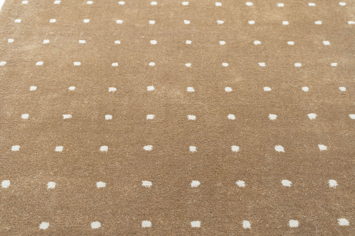 Hem Rug close up, hand tufted New Zealand wool in camel scattered with small ivory dots.