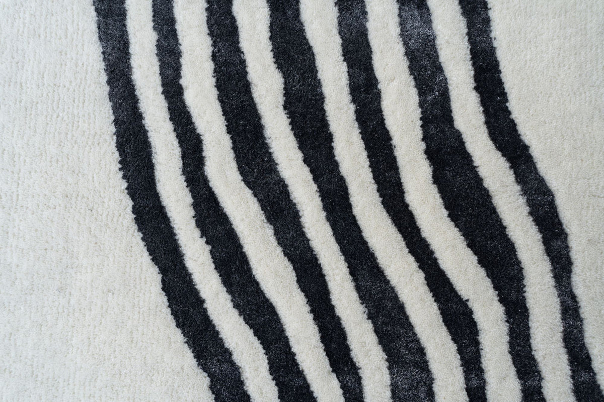 Livid Wool & Silk Rug close up, charcoal contour lines of New Zealand wool and Botanical Silk curving across an ivory field.