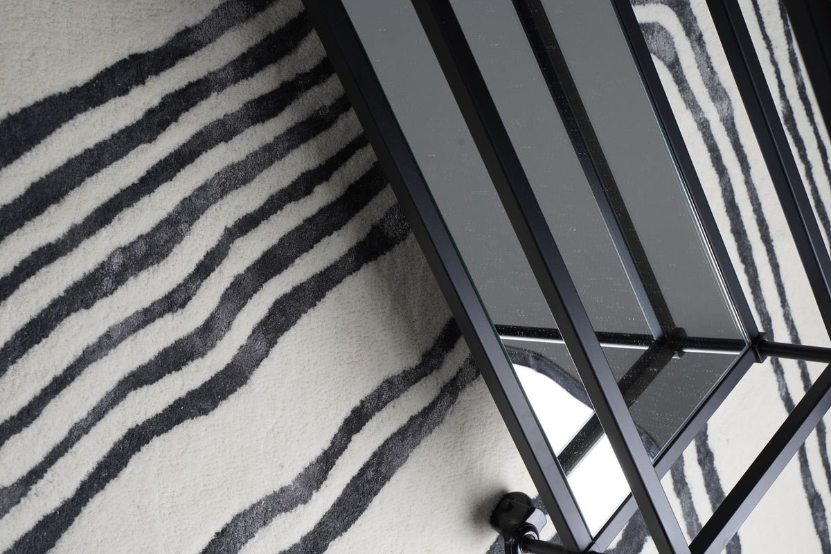 Livid Wool & Silk Rug seen from above beside a black metal frame, dark clouded lines in hand tufted New Zealand wool and Botanical Silk.