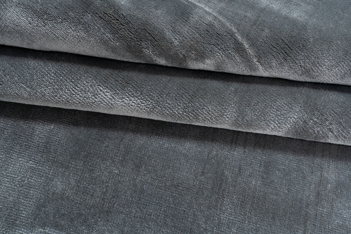 Luma Silk Rug in Charcoal folded in soft layers, handloom Botanical Silk with a deep grey sheen.