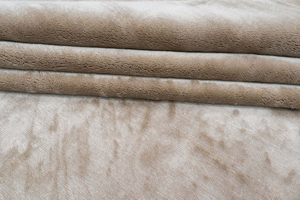 Luma Silk Rug in Greige folded in soft layers, handloom Botanical Silk with a pale, shifting sheen.