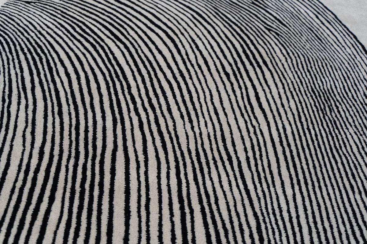 Monochrome Wool Rug close up, hand tufted New Zealand wool, dense black lines curving across an ivory ground.