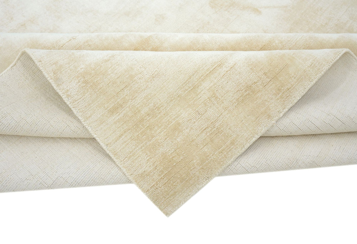 Nuva Silk Rug in Beige folded at the corner, handloom Botanical Silk with a pale, soft sheen.