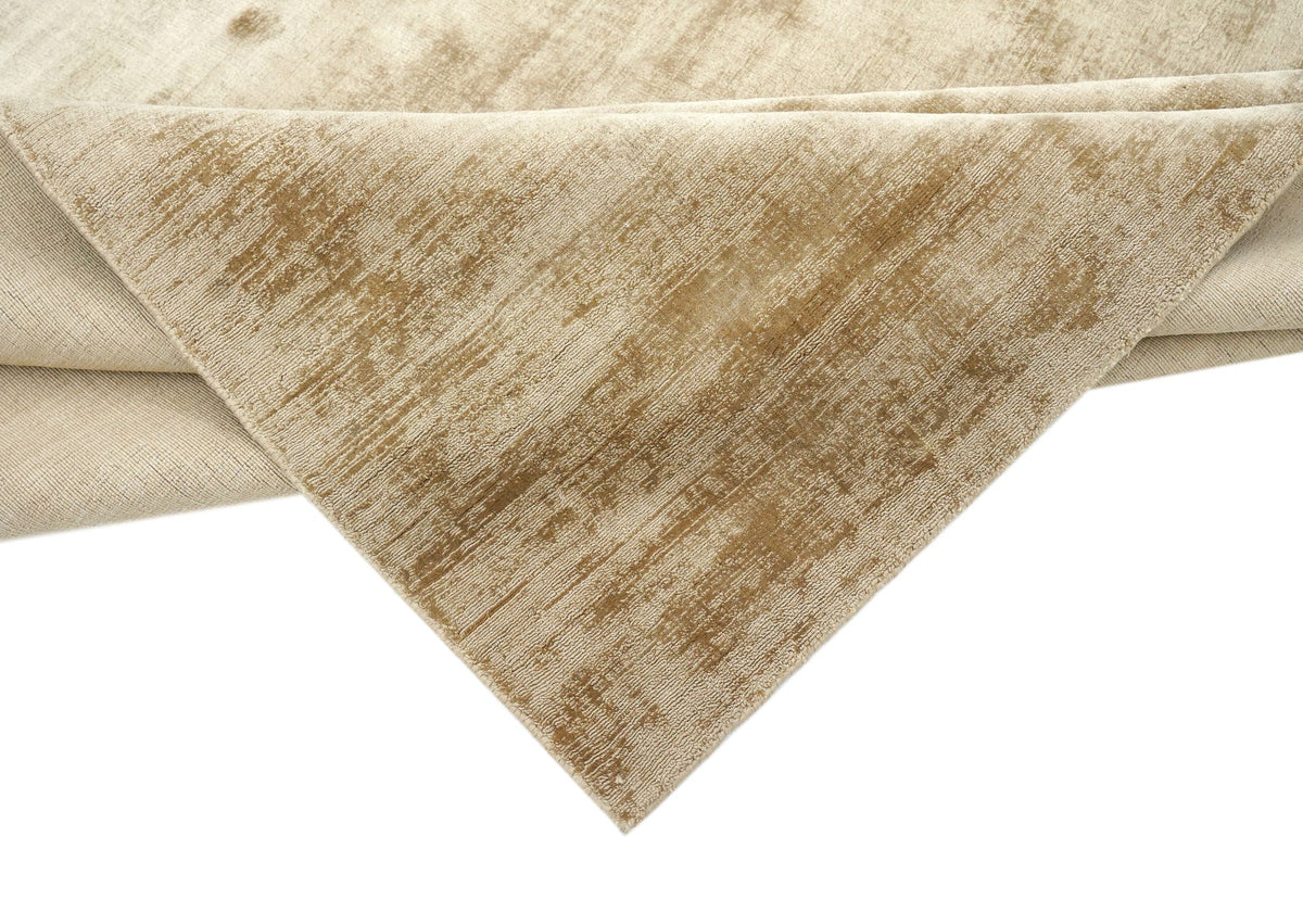 Nuva Silk Rug in Camel folded at the corner, handloom Botanical Silk with a warm golden sheen.