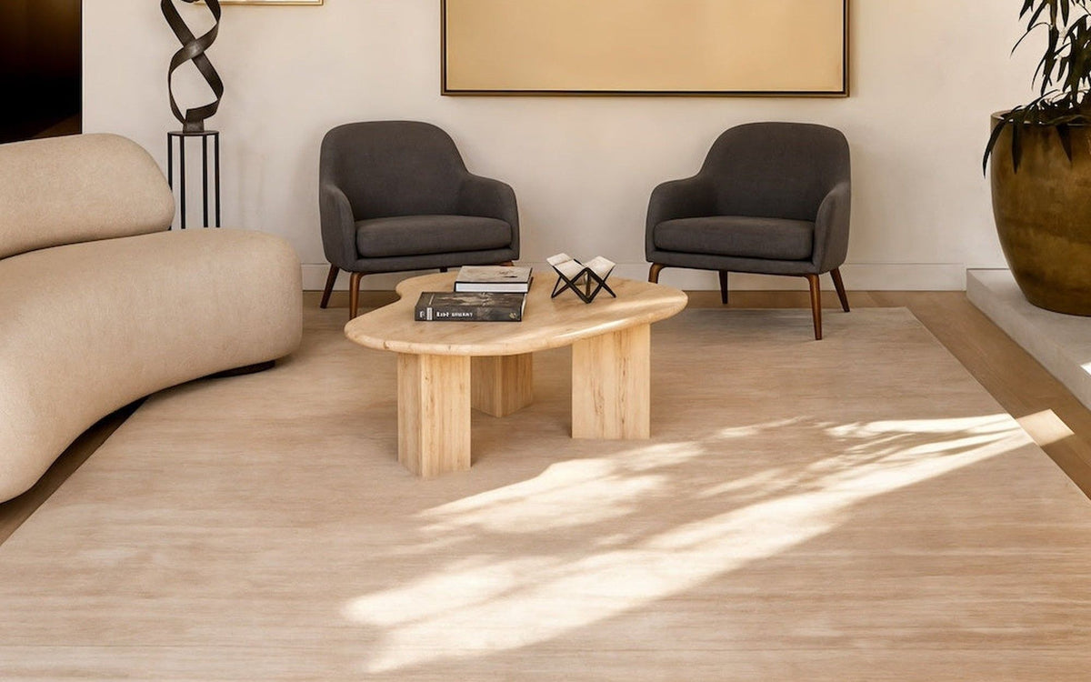 Plush Wool Rug in Sand in a living room, a deep handloom wool pile under a curved cream sofa and two grey armchairs.