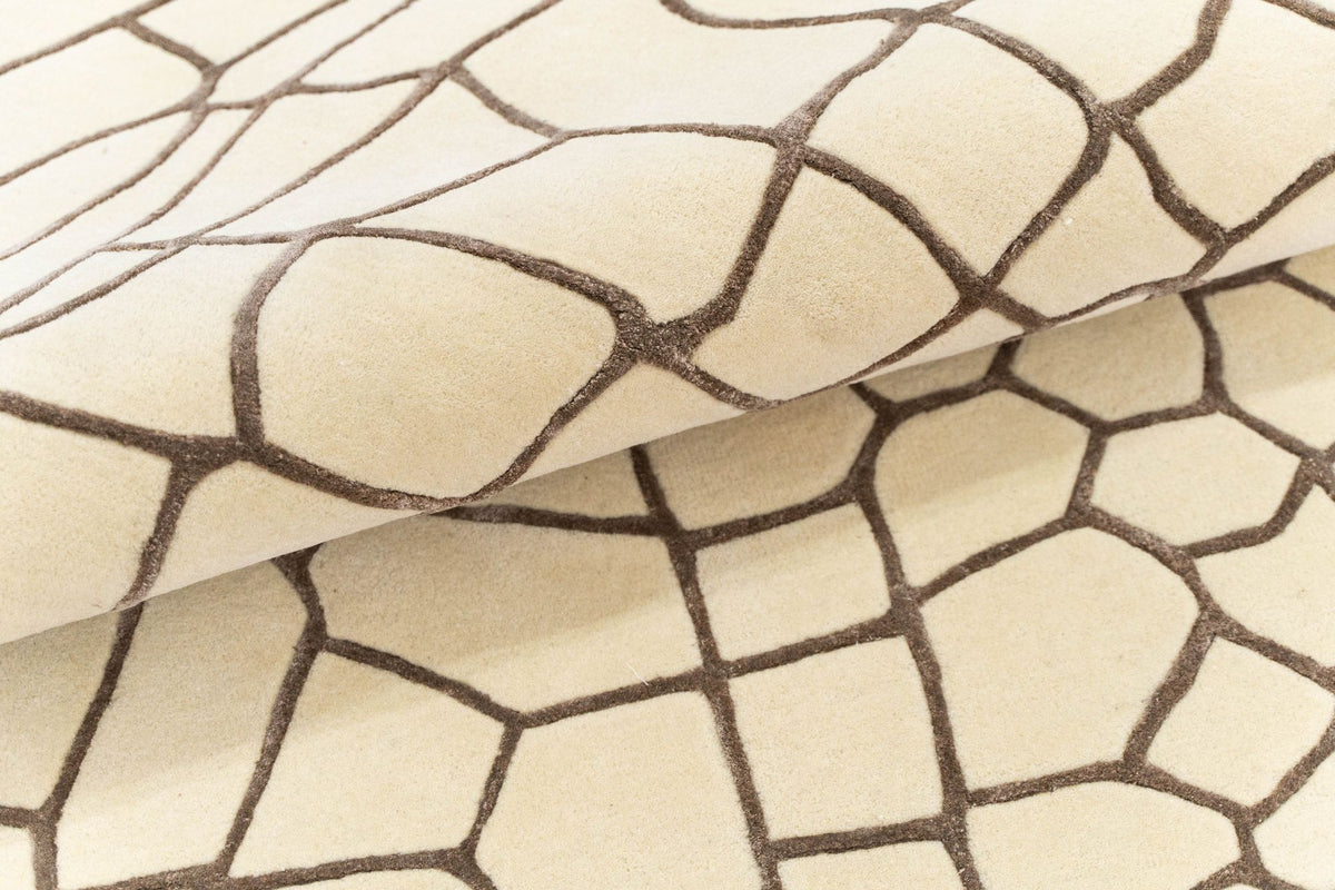 Terraform Wool & Silk Rug folded over itself, a pale hand tufted wool field crossed by a network of fine brown lines.