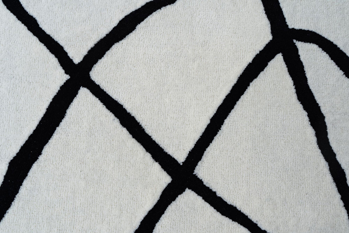 Tinker Wool Rug close up, ivory hand tufted New Zealand wool with black lines crossing the field.