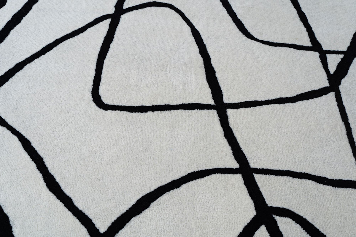 Tinker Wool Rug close up, black hand drawn lines looping across ivory hand tufted New Zealand wool.