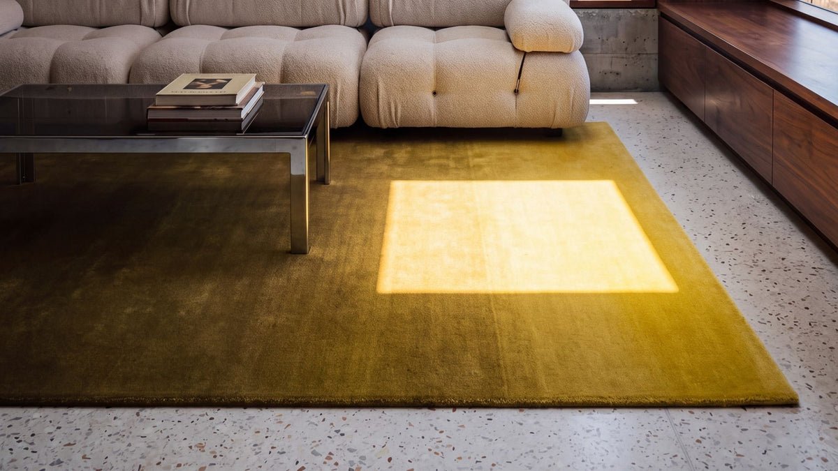 Ombré Solitude Rug in a concrete and walnut living room at noon, an ochre gradient in hand tufted wool.