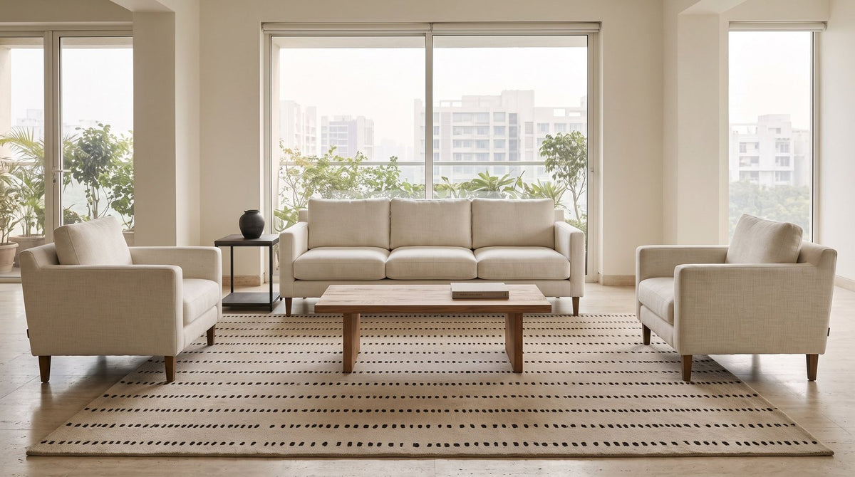 Greige Wool Rug under a three seater and two armchairs in a styled living room, every front leg on the rug. Room is a digital render; the rug is from a product photo.