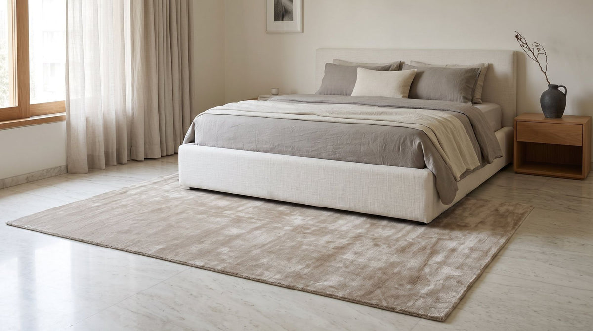 Luma Silk Rug in Greige in a calm bedroom, handloom Botanical Silk on a pale marble floor.